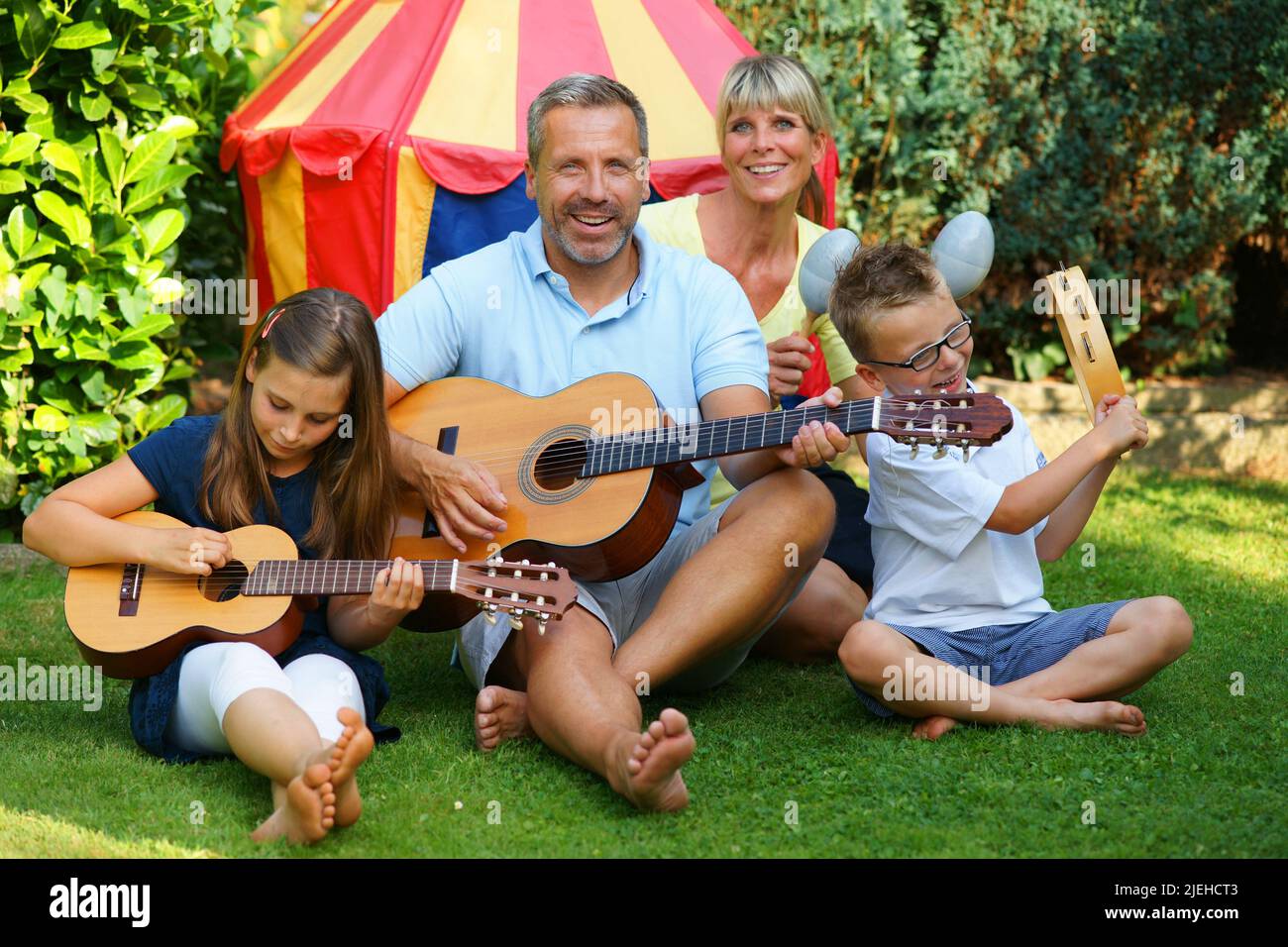 Eine glückliche Familie macht im Garten Musik, zeltet, Camping, Mann, Frau, Zwei Kinder, 4 Personen, Foto Stock