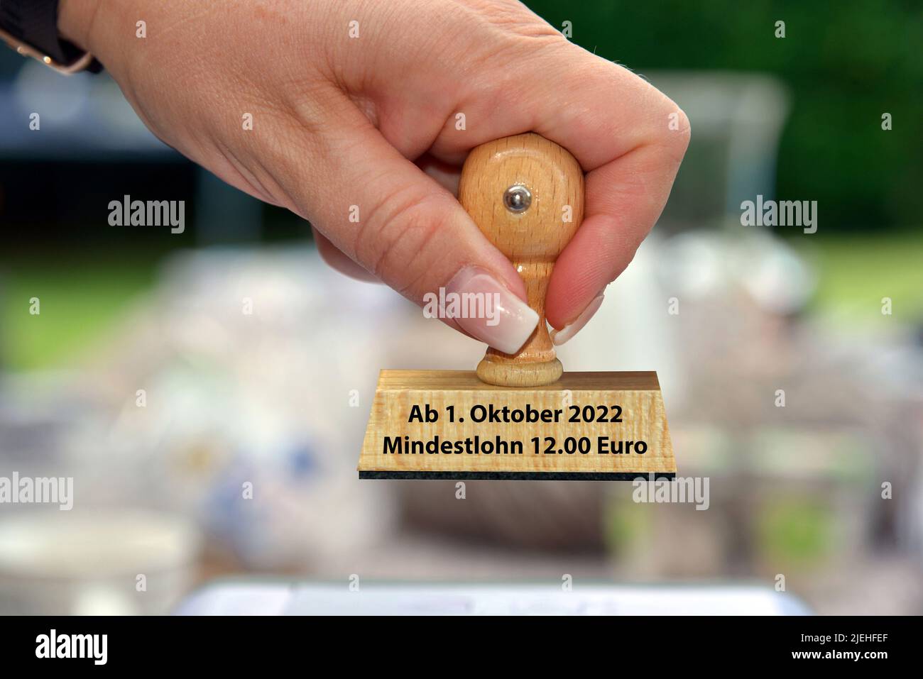 Eine Hand mit Stempel, Frauenhand, Aufschrift: Minerdestlohn ab 1. Ottobre 2022 = 12,00 Euro Foto Stock