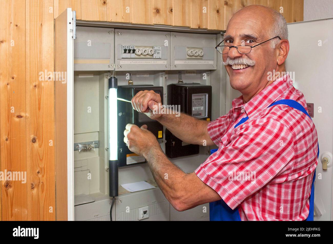 Ein Elektriker arbeitet am Sicherungskasten, Stromzähler, Überprüfung, Installazione, Senior, 65, 70, Jahre, Schaltkasten, Installazione, Strom, Energie Foto Stock