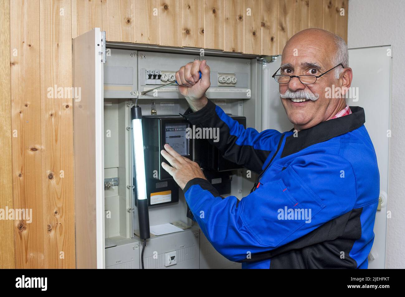 Ein Elektriker arbeitet am Sicherungskasten, Stromzähler, Überprüfung, Installazione, Senior, 65, 70, Jahre, Schaltkasten, Installazione, Strom, Energie Foto Stock