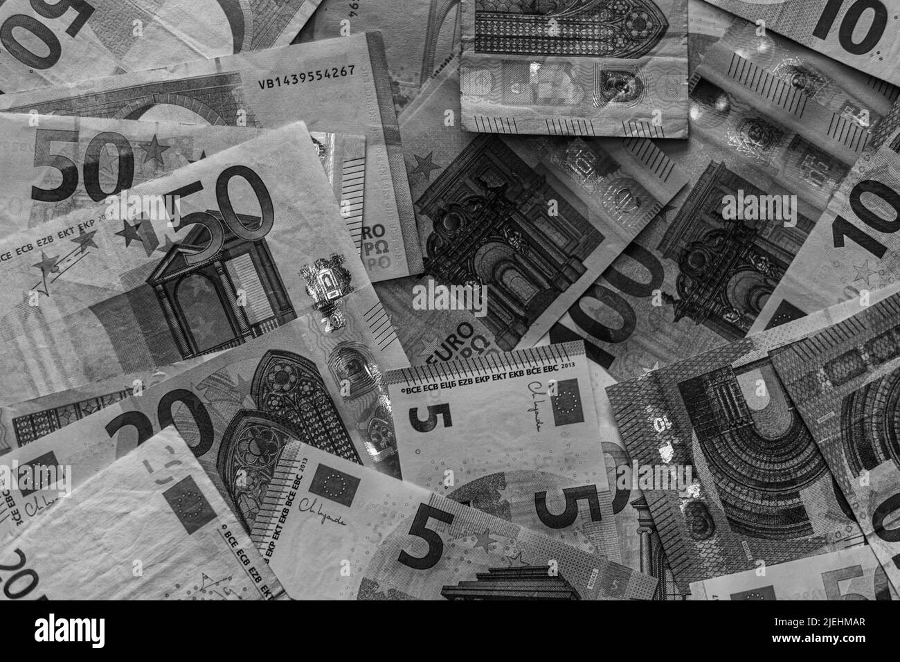 Le banconote in euro si diffondono in modo casuale in bianco e nero, perdendo valore a causa dell'inflazione Foto Stock
