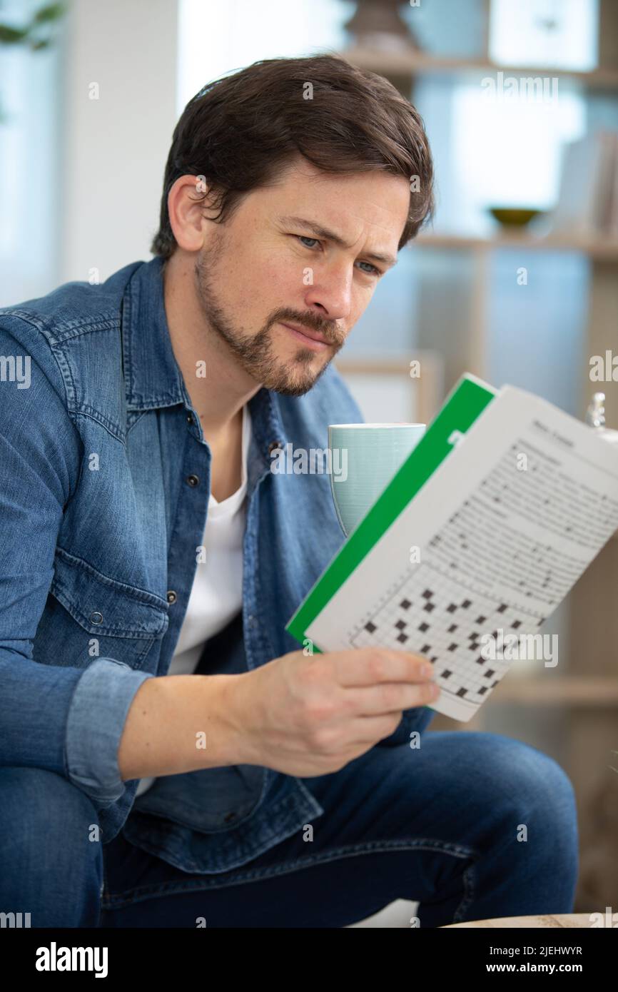 uomo che fa le cruciverba a casa Foto Stock