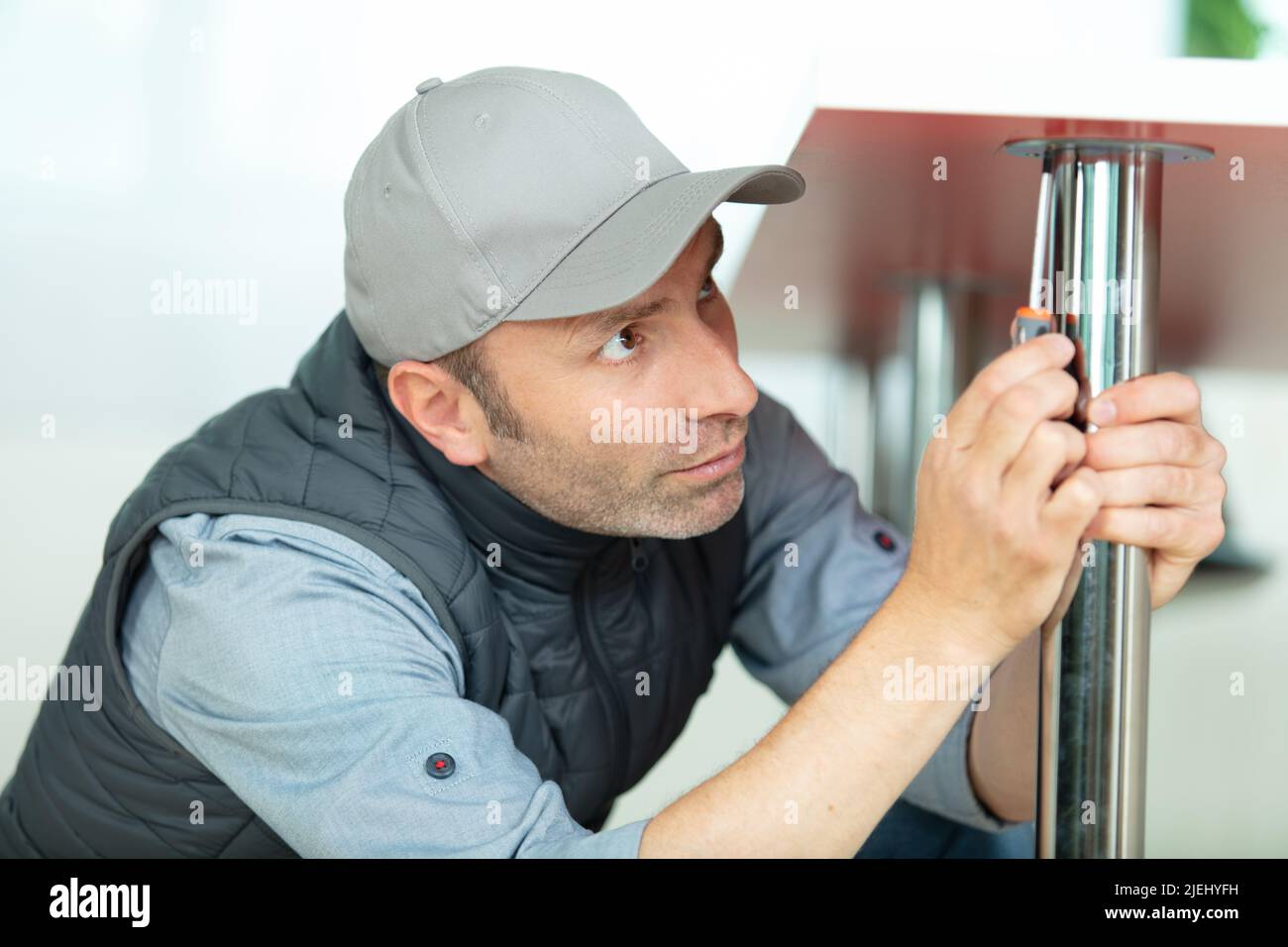 uomo che fissa la gamba di un tavolo Foto Stock
