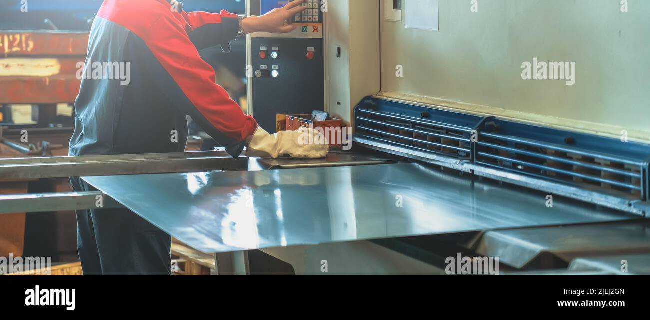 L'operatore controlla la macchina per la lavorazione dei metalli in fabbrica. Foto Stock