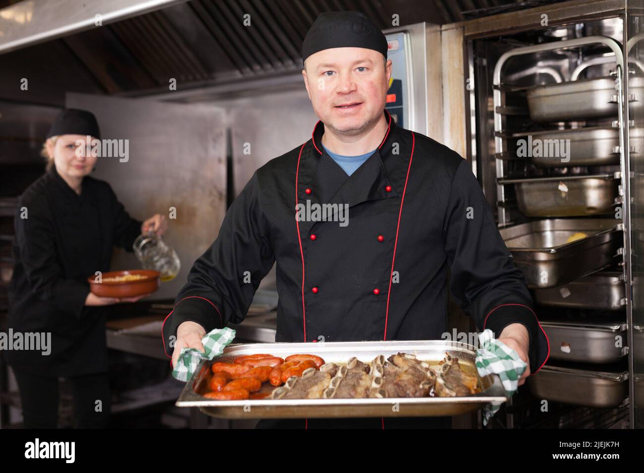 Lo chef prepara il piatto di carne fuori dal forno Foto Stock