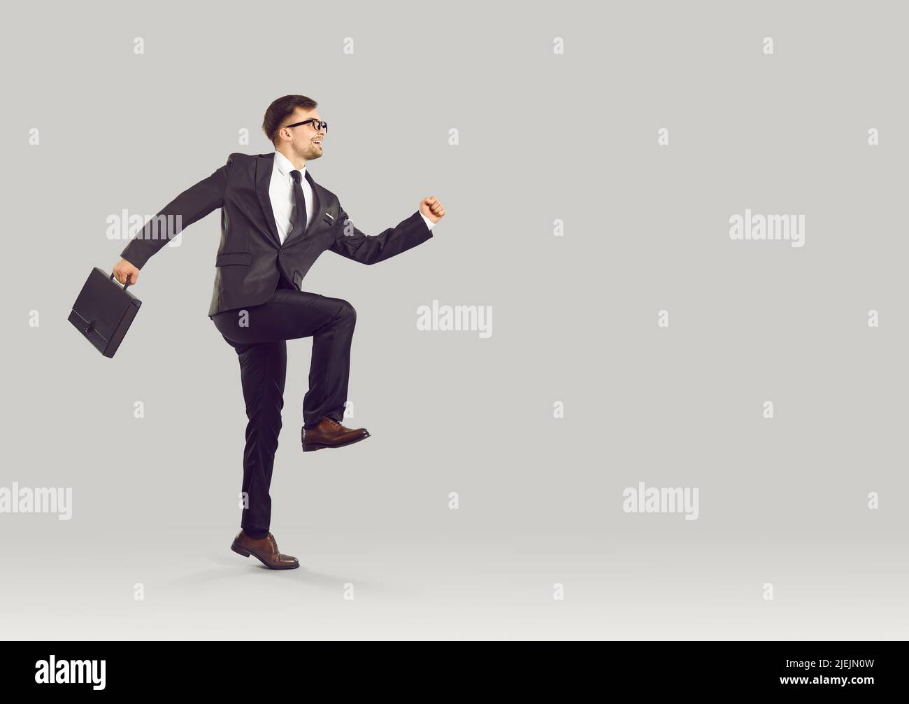 Divertente dipendente aziendale felice con business briefcase in esecuzione per iniziare la sua giornata di lavoro Foto Stock