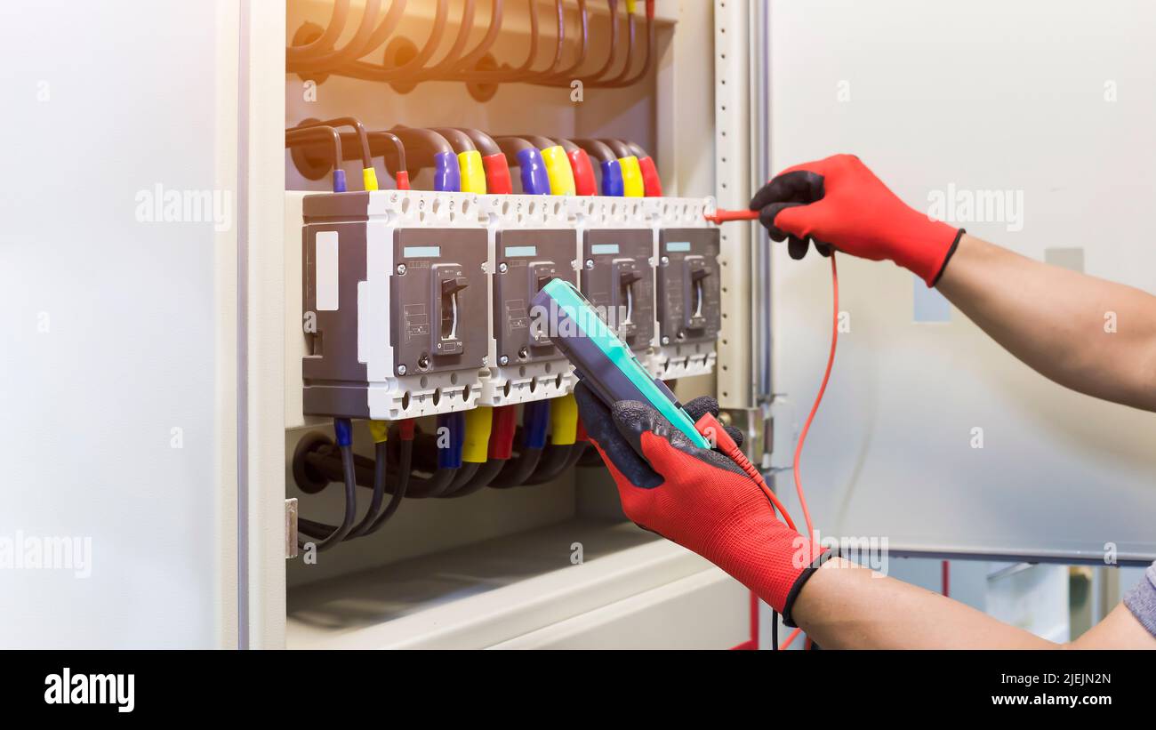 I tecnici elettrici controllano i dispositivi di controllo elettrici con un multimetro. Foto Stock