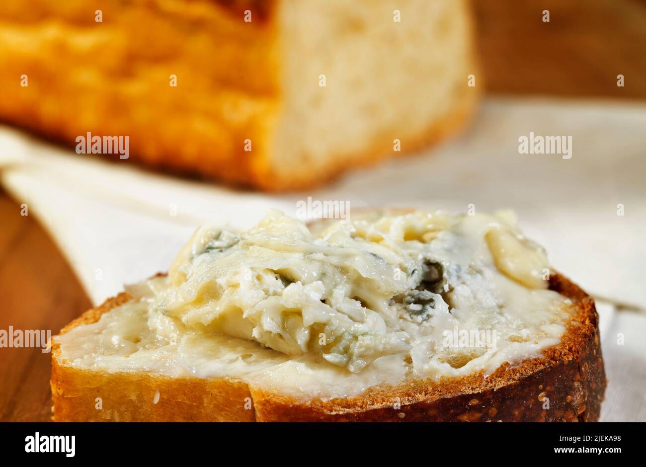 Gorgonzola spalma su fette di pane , sullo sfondo una pagnotta di pane , pronta a mangiare Foto Stock