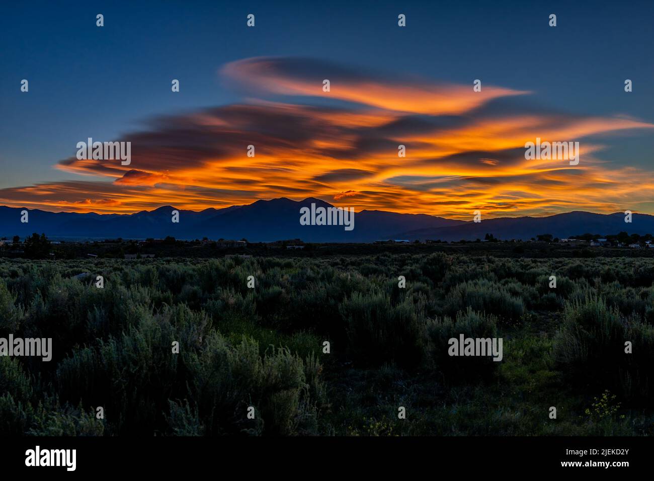 Rosso scuro alba e verde deserto salvia piante a spazzola in Ranchos de Taos paesaggio valle in estate con sole nuvole drammatico tempo in New Mexico, Foto Stock