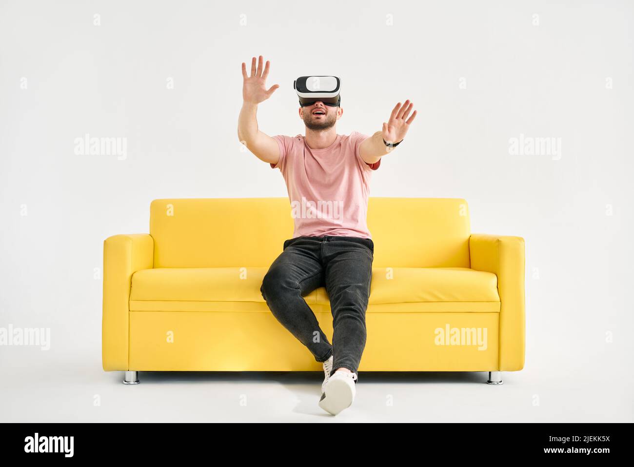Giovane uomo che indossa cuffie per realtà virtuale per giocare ai videogiochi e provare a toccare qualcosa con le mani Foto Stock