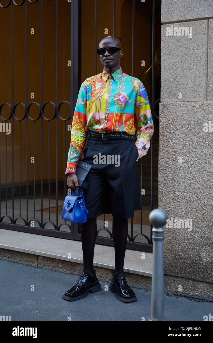 MILANO, ITALIA - 18 GIUGNO 2022: Uomo con borsa Versace in pelle blu,  camicia colorata e pantaloncini neri prima della sfilata di moda Versace,  Milano Fashion Week stree Foto stock - Alamy