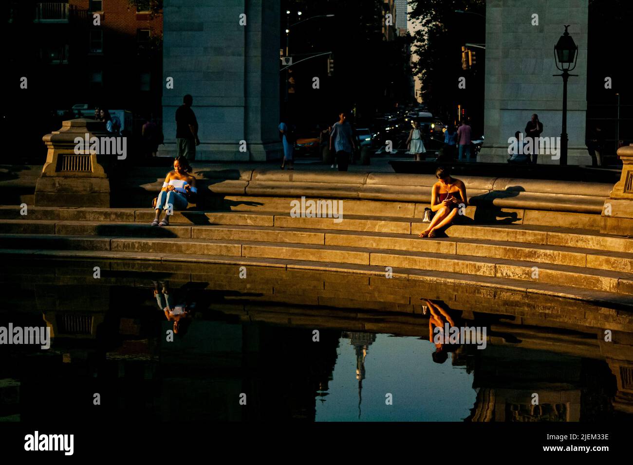 Due donne si sono riflesse nella fontana del Washington Square Park a New York City Foto Stock