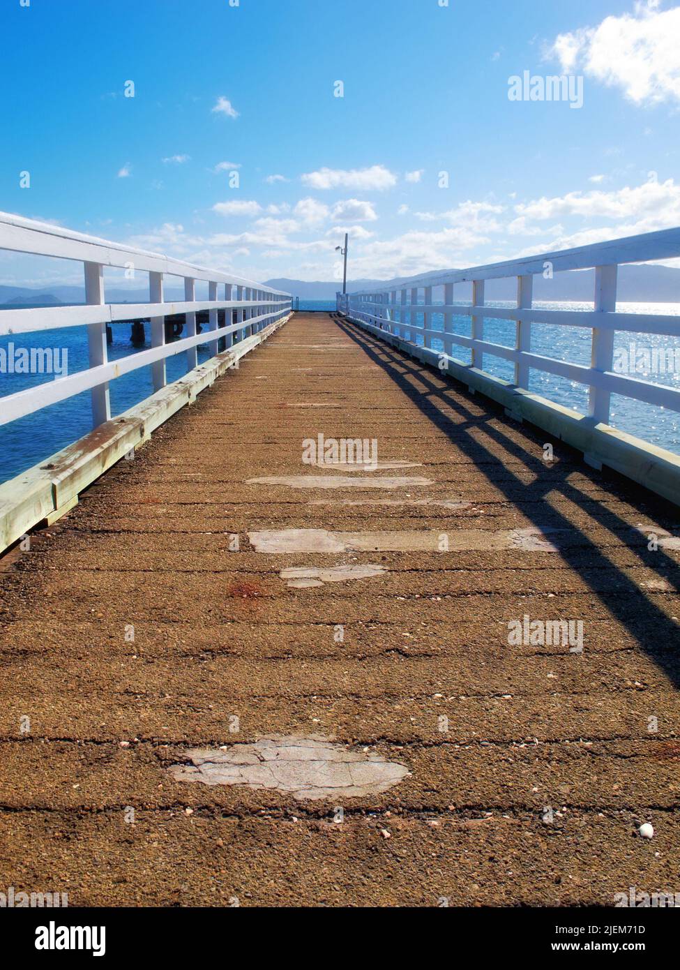 Un molo di legno che conduce all'oceano con spazio copia. Una vecchia piattaforma vuota o terrazza di banchina su un lago con acqua blu. Jetty di legno, vecchio ponte o un Foto Stock