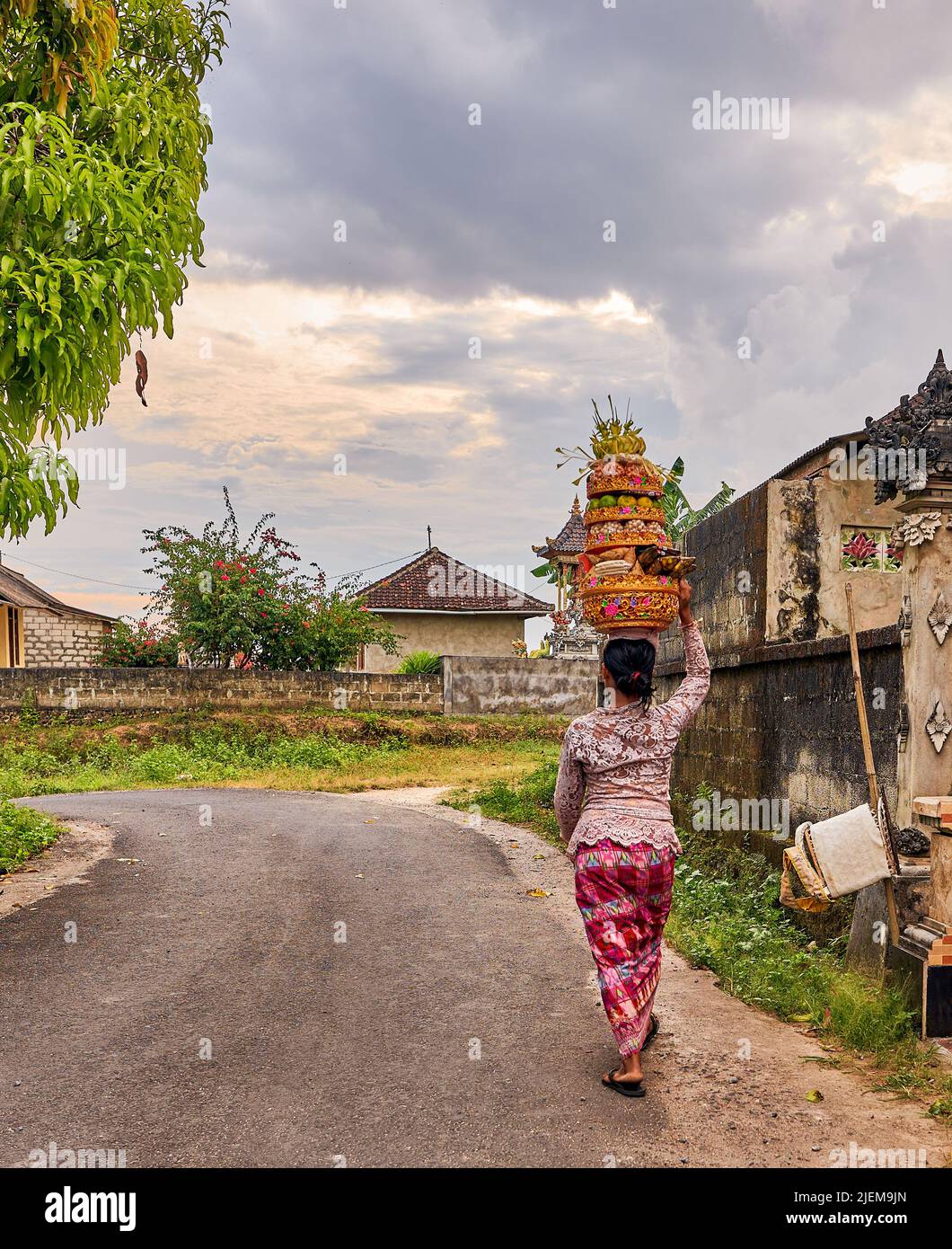 Donna che cammina su una strada che porta cesti con frutta sulla testa. Foto Stock