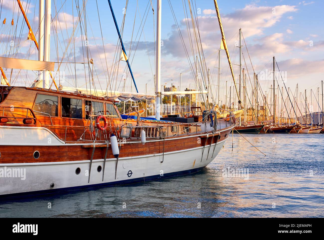 Gruppo di barche ormeggiate in un porto di Bodrum in Turchia al tramonto. Vista panoramica degli yacht a vela nel porto delle navi da crociera e la baia al tramonto. Cantiere navale vuoto all'interno Foto Stock