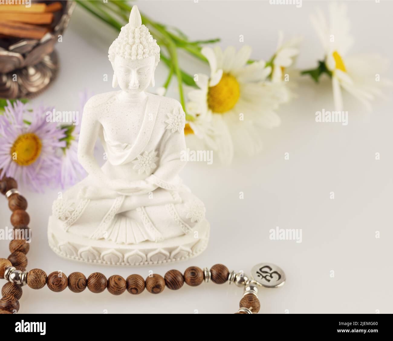 Statua del Buddha, perle di preghiera, bastoni di aroma e fiori su sfondo bianco procedura rituale termale asiatica, guarigione e meditazione. Salute energetica e r Foto Stock
