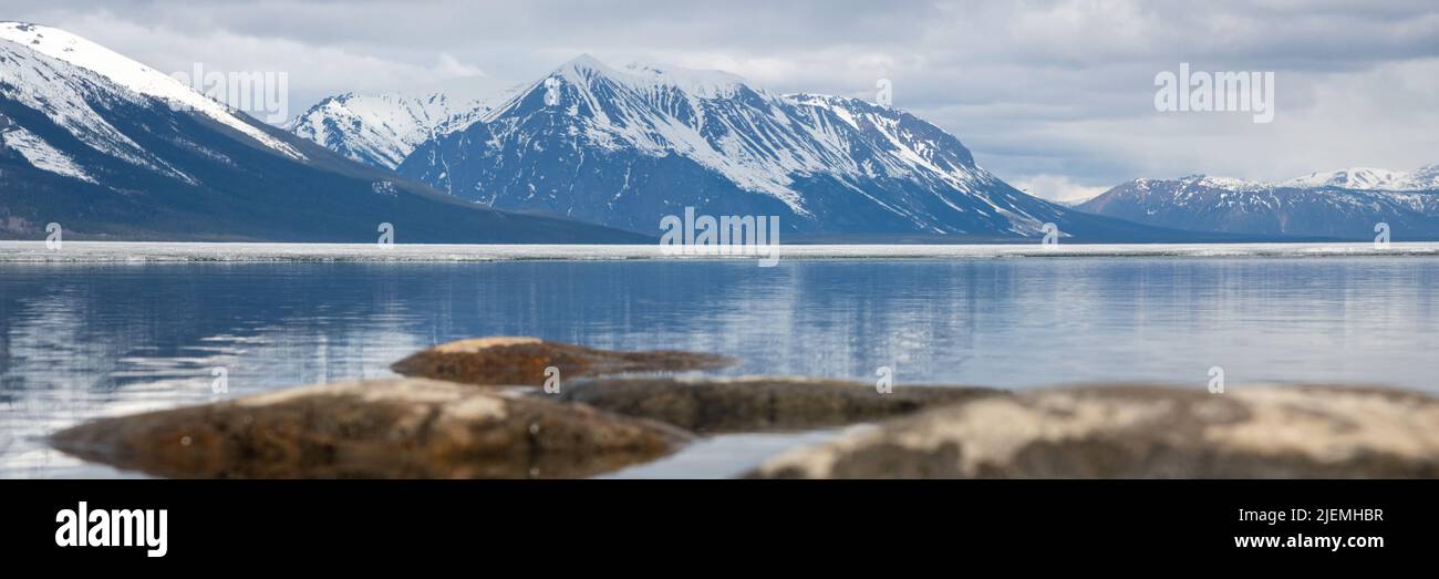 Splendide scene primaverili nella Columbia Britannica settentrionale durante la primavera con lago e montagne innevate in riflessione. Foto Stock