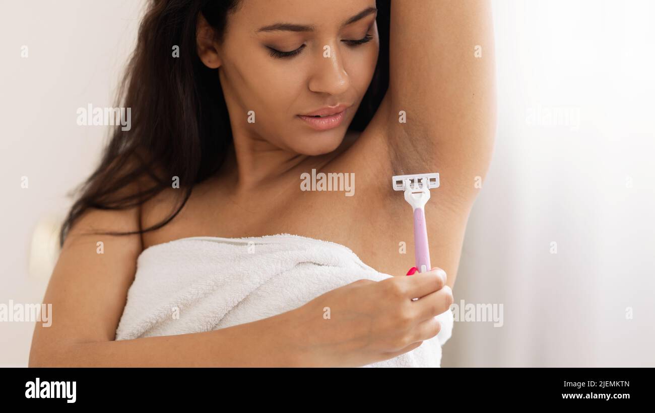 Attraente Donna rasatura capelli ascella con Razor di sicurezza in bagno Foto Stock