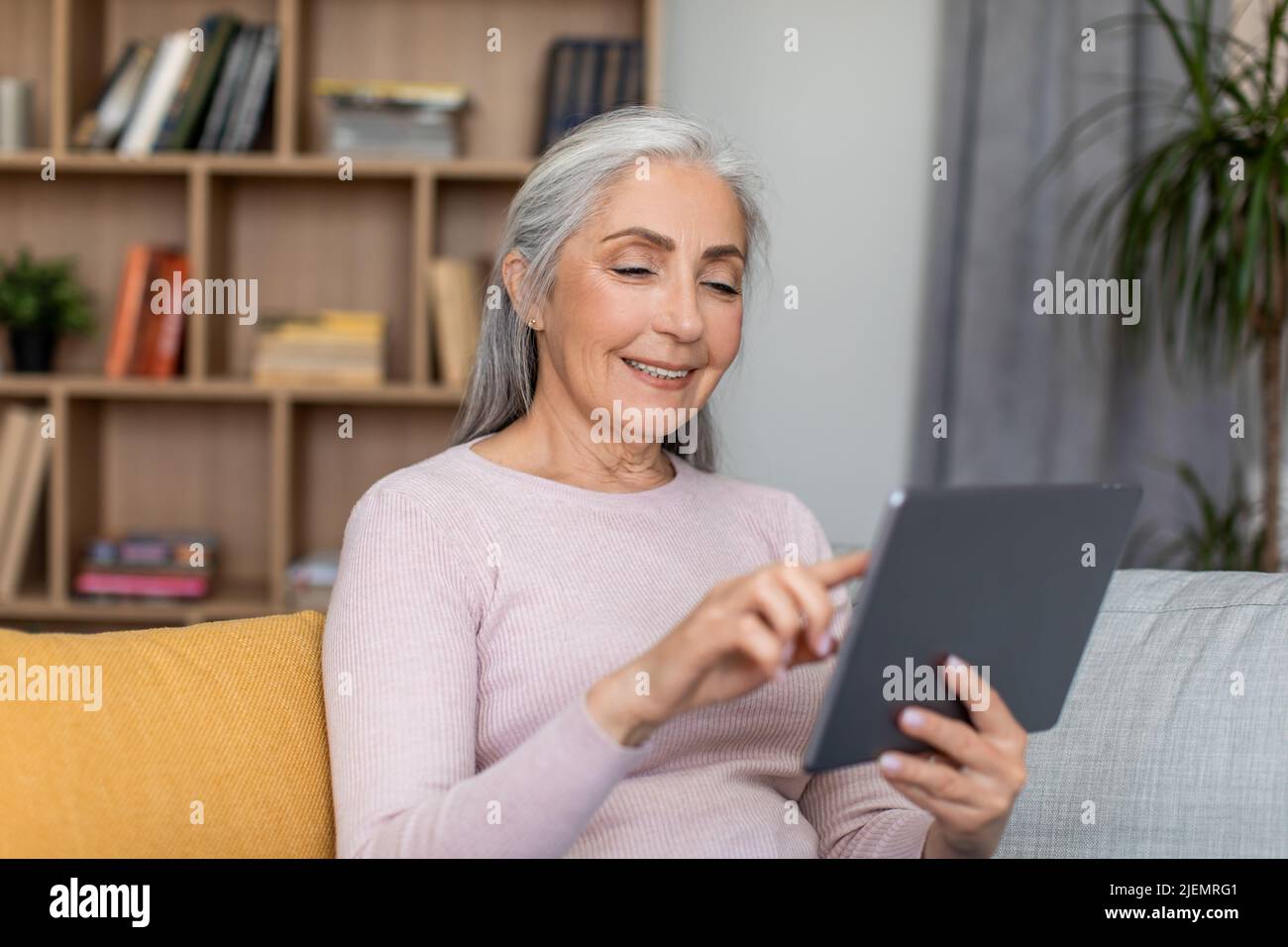 Felice sorridente europea anziana con capelli grigi hanno riunione a distanza, chat e guardare video sul tablet Foto Stock