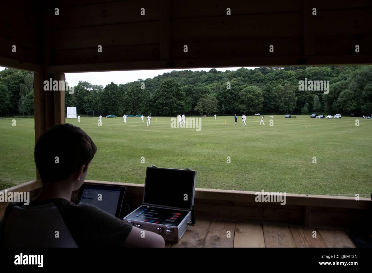 Vista dalla casella scorers come il marcatore registra elettronicamente il progresso e di una partita di cricket villaggio in una partita di campionato di cricket nello Yorkshire Foto Stock