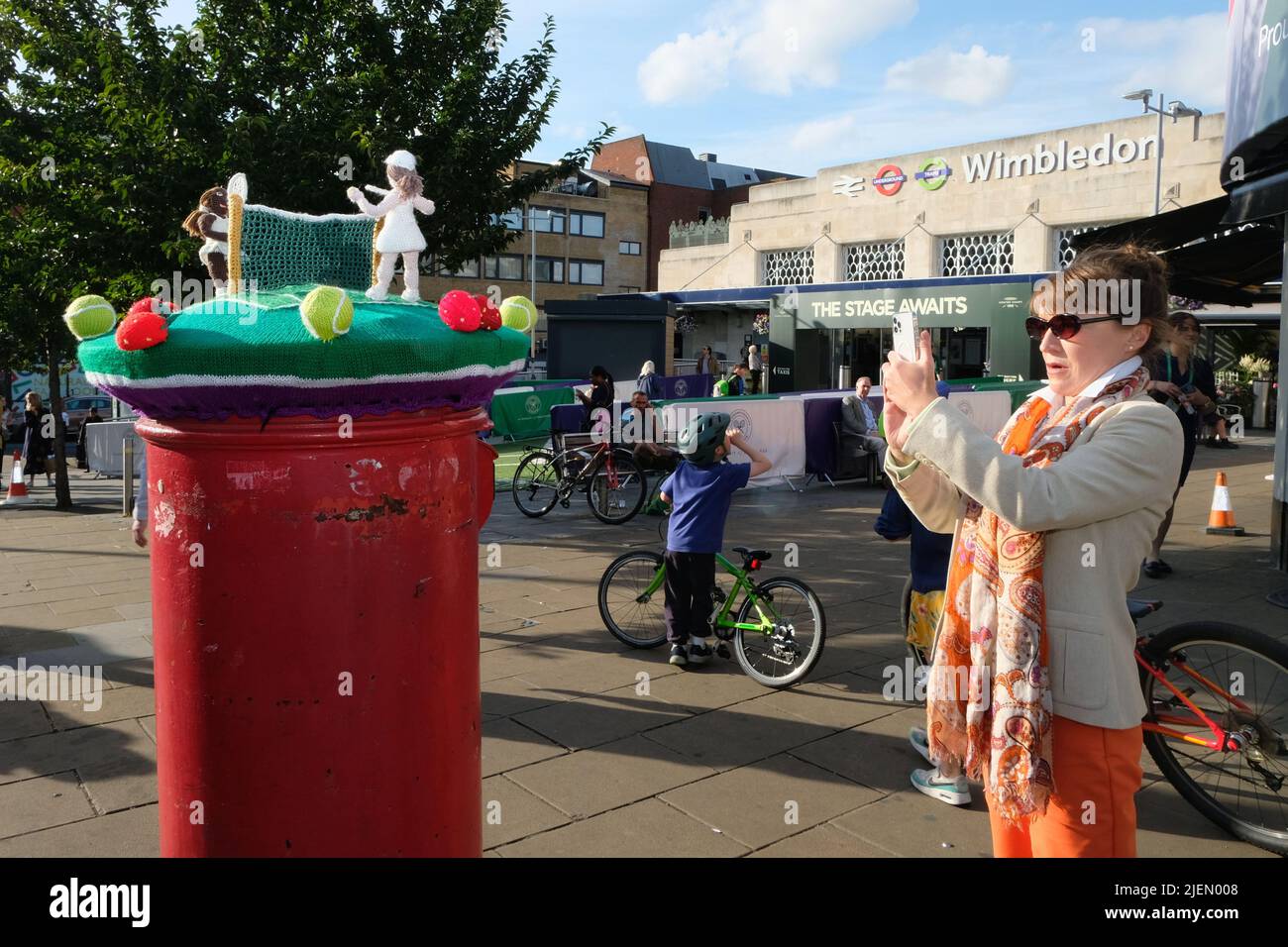 Londra, Regno Unito, 27th giugno 2022. Io donna scatta una foto di un topper da cartolina a tema tennis. All'inizio del torneo di tennis del 2022, nel villaggio di Wimbledon e nel centro principale della città si possono vedere mostre speciali. Quest'anno, dopo la pandemia del Covid, il terreno torna a piena capacità. Credit: Undicesima ora Fotografia/Alamy Live News Foto Stock