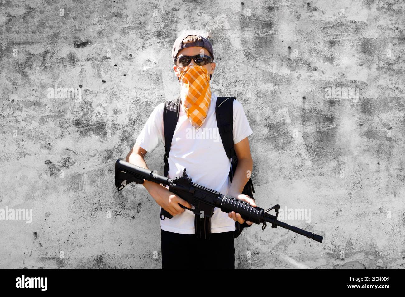 Un bambino con una bandana che tiene un fucile. Concetto di sparatutto per la scuola. Foto Stock