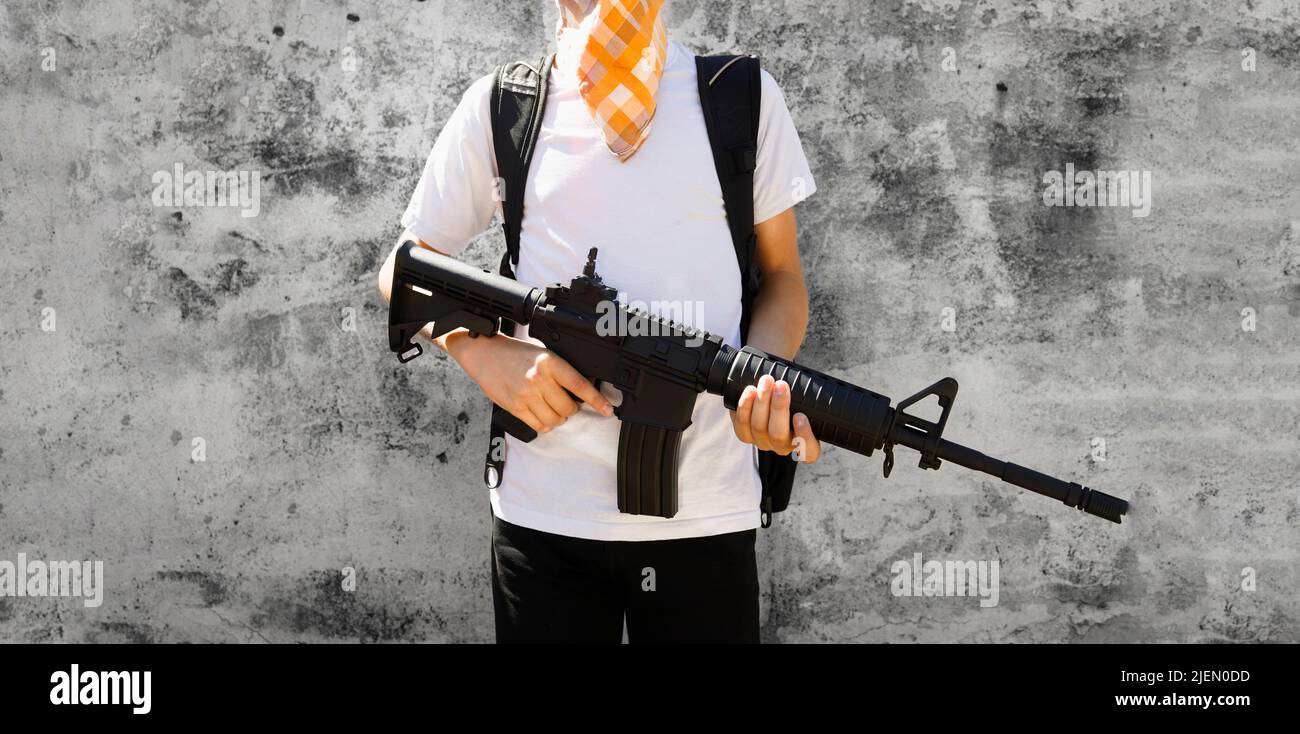 Dettaglio di un bambino della scuola che tiene un fucile automatico. Concetto di sparatutto per la scuola. Foto Stock