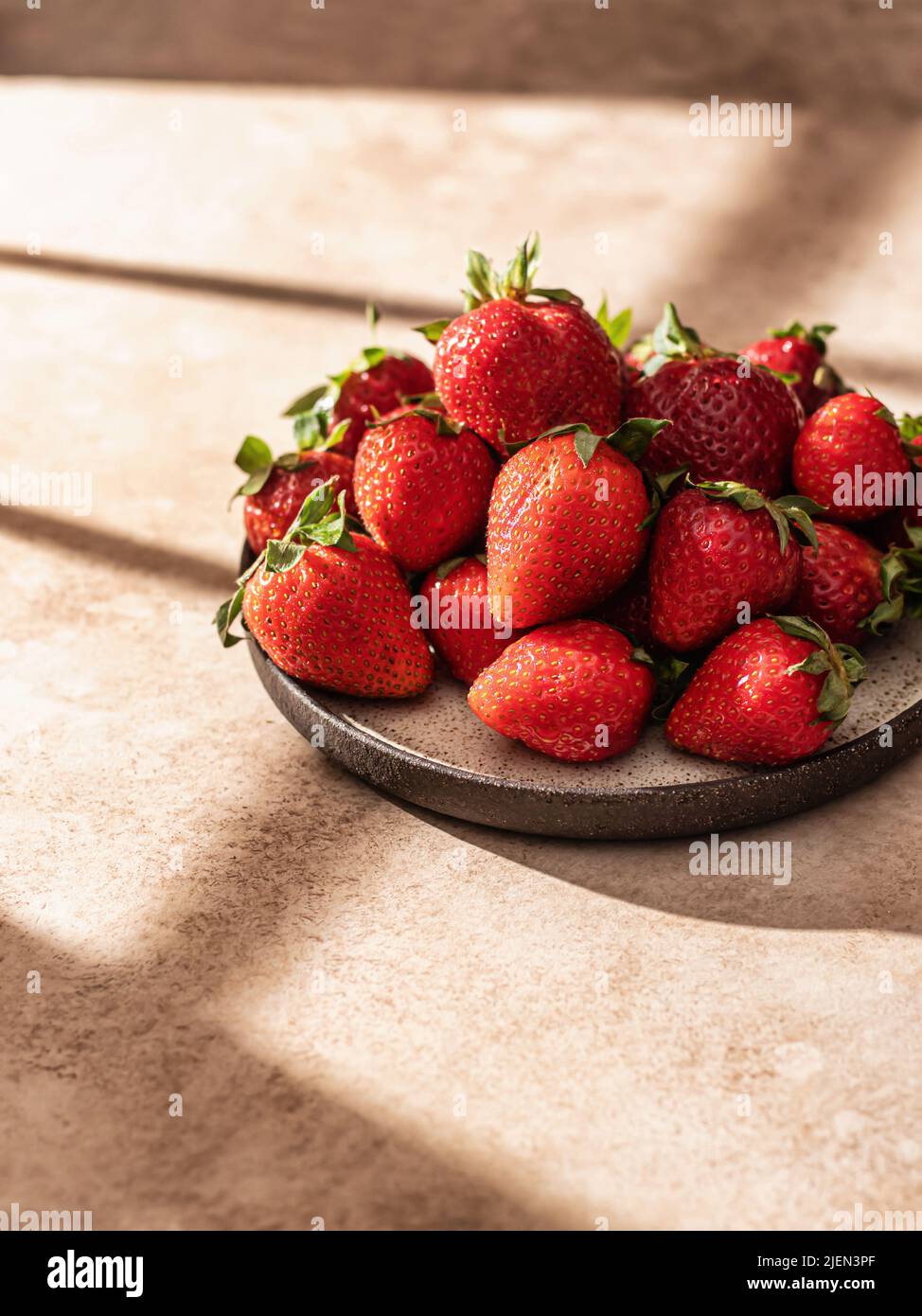 Fragola in piatto con ombre della finestra di hursh. Estetica creativa minimalista, spazio testo. Orientamento verticale Foto Stock