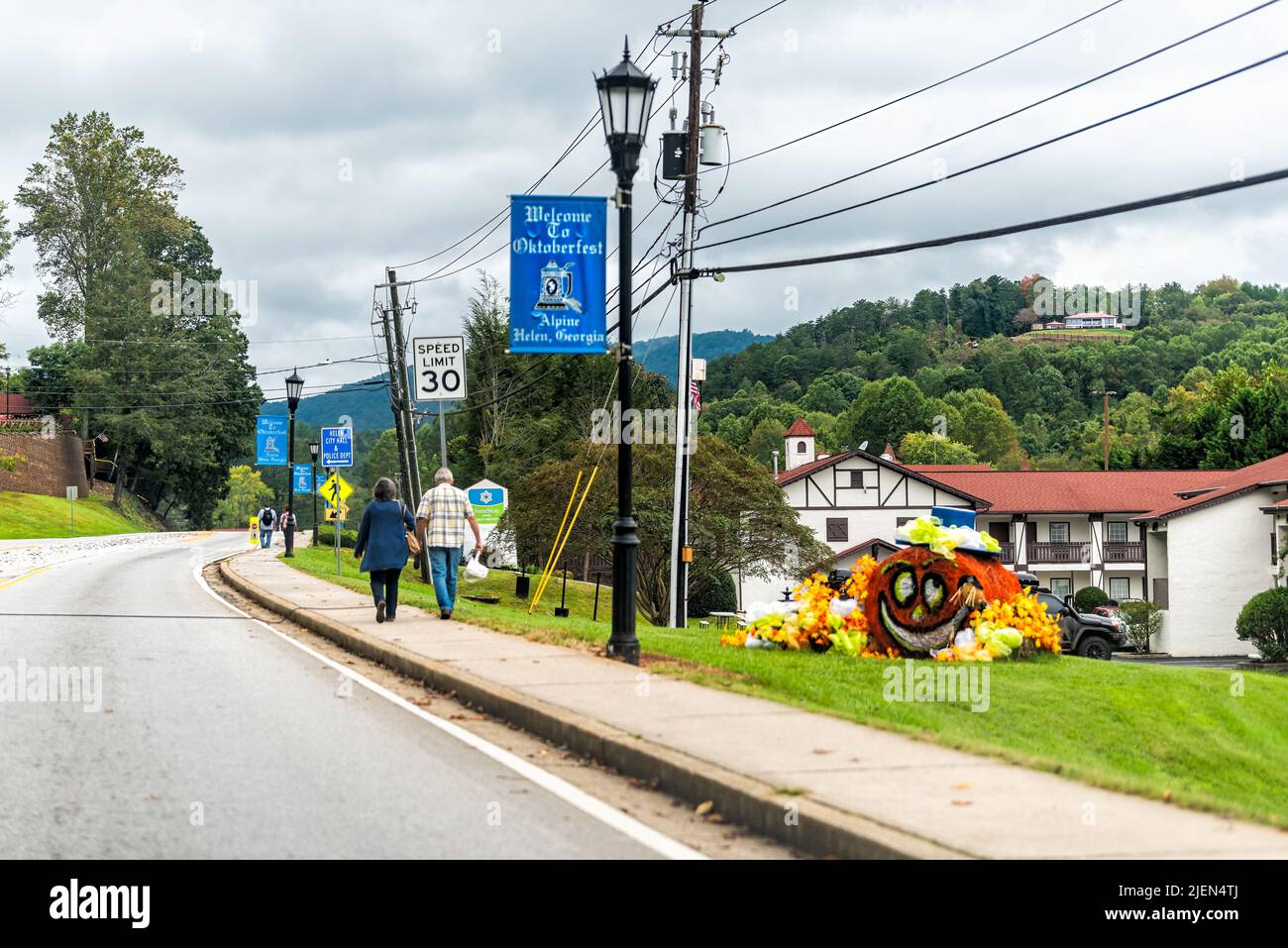 Helen, USA - 5 ottobre 2021: Helen, Georgia strada del villaggio bavarese con una coppia che cammina sul marciapiede al festival Oktoberfest che guida il punto auto di Foto Stock