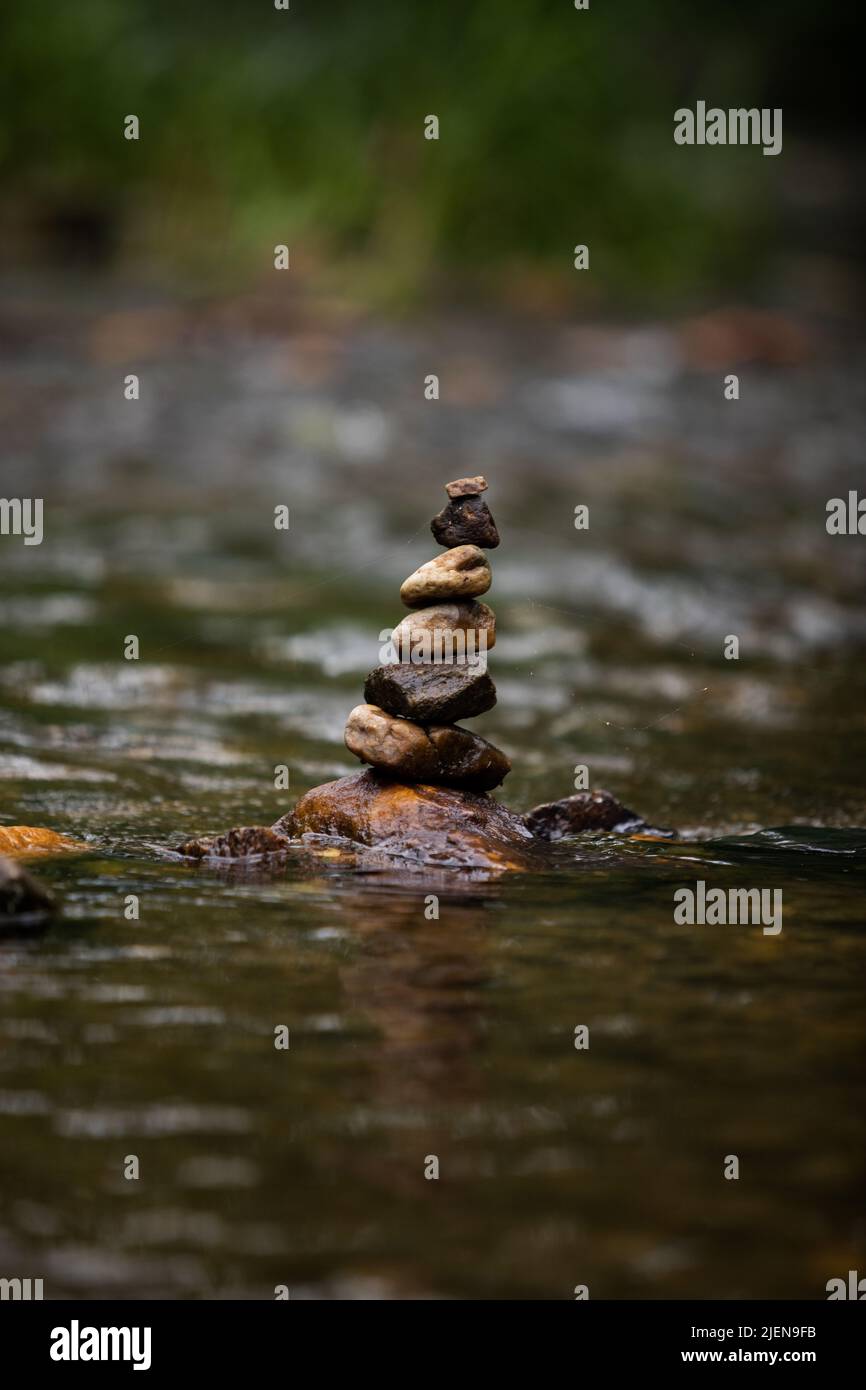 Pietre accatonate con cura sul fiume che scorre dolcemente Foto Stock
