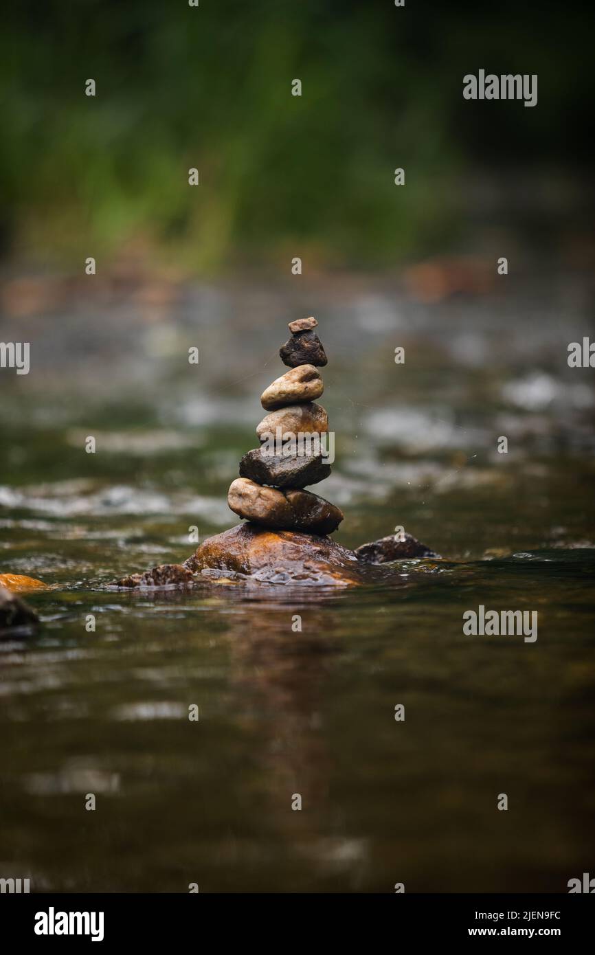 Pietre accatonate con cura sul fiume che scorre dolcemente Foto Stock