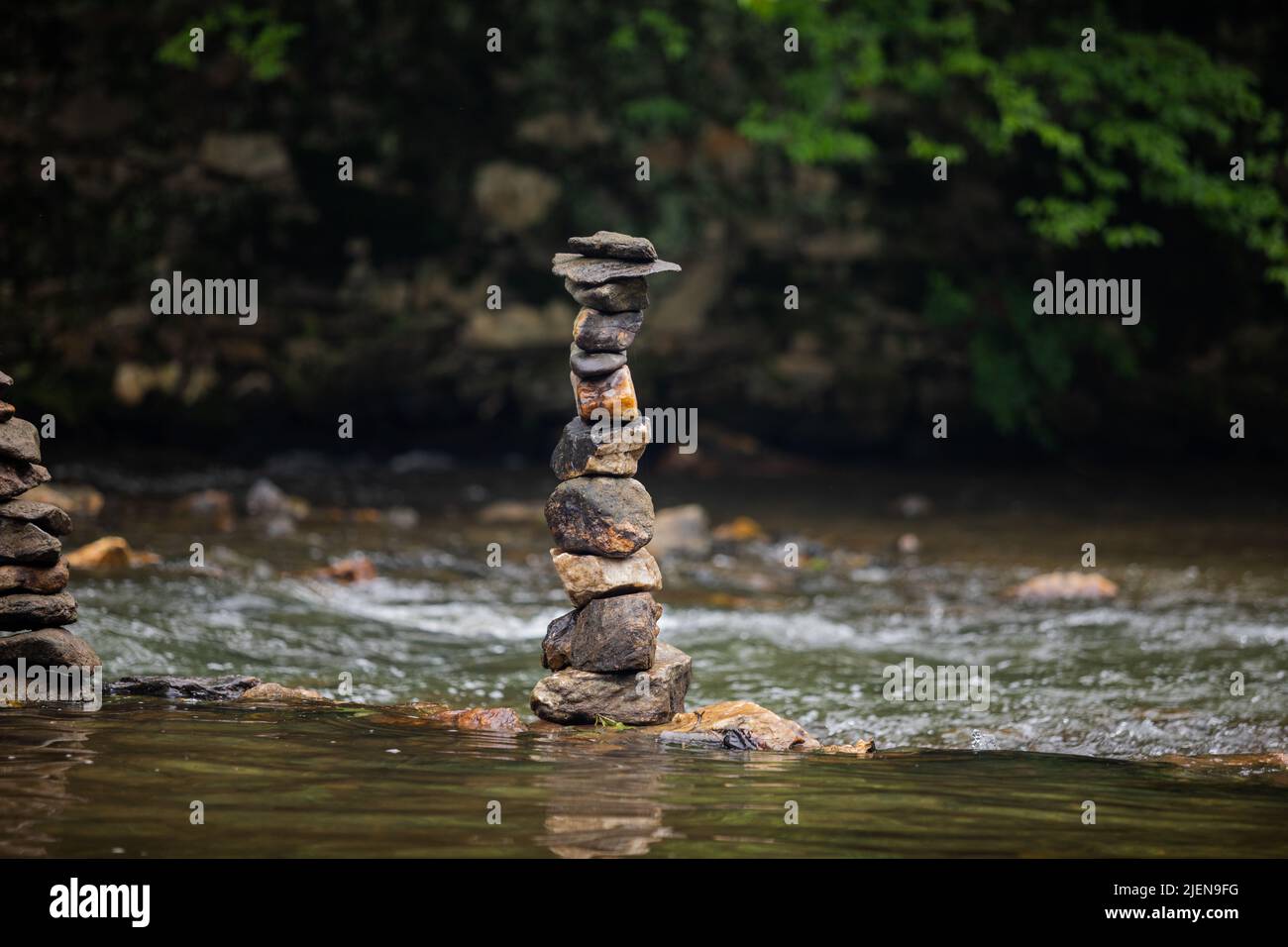 Pietre accatonate con cura sul fiume che scorre dolcemente Foto Stock