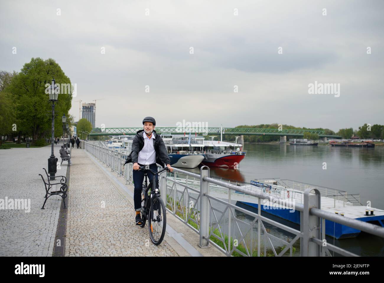 Uomo d'affari che viaggia per lavoro, in bicicletta sul ponte, concetto di stile di vita sostenibile. Foto Stock