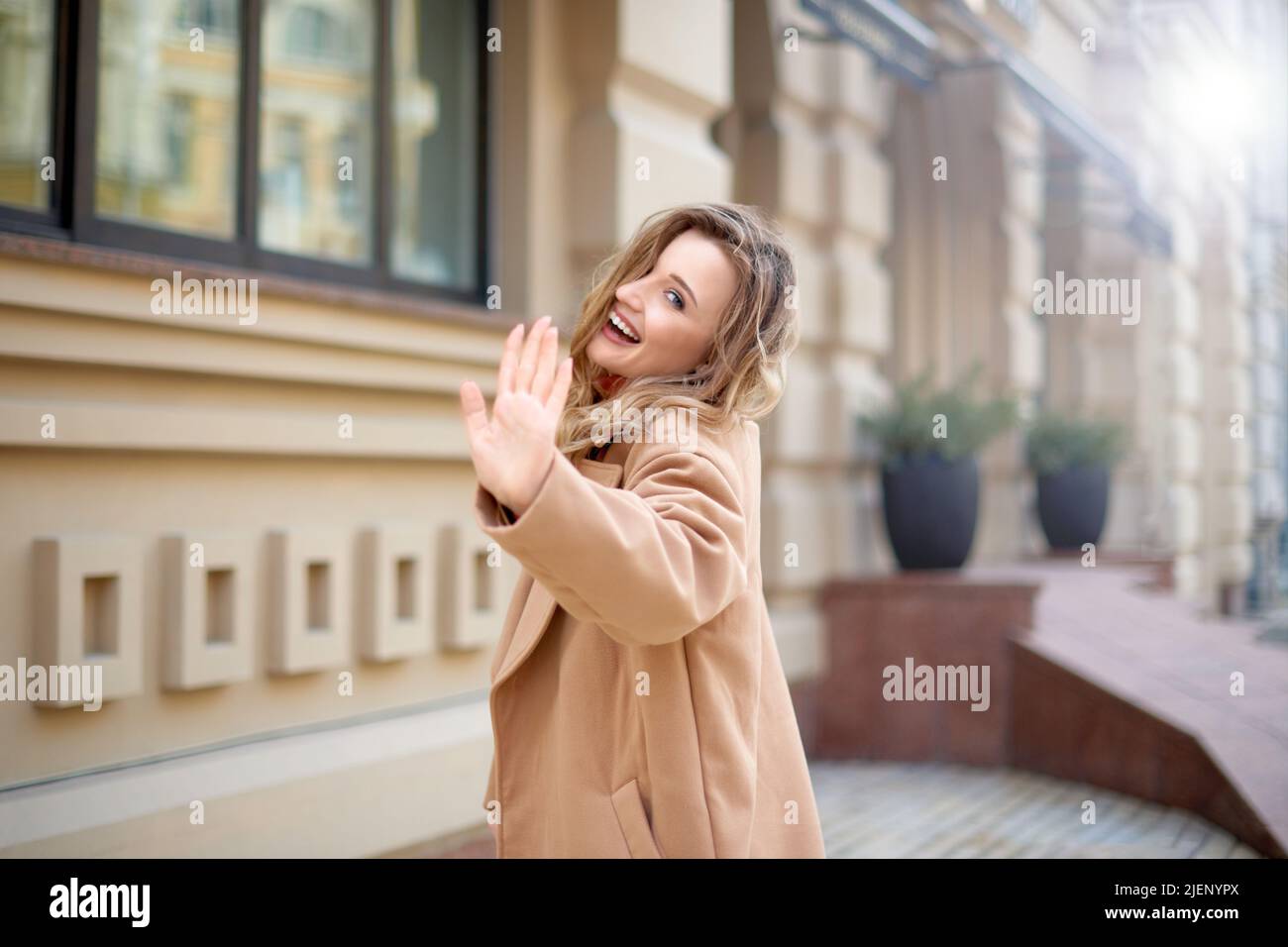 donna cammina sulla strada della città e ondeggiando Arrivederci o Ciao. donna mano gesto saluto o bye Foto Stock