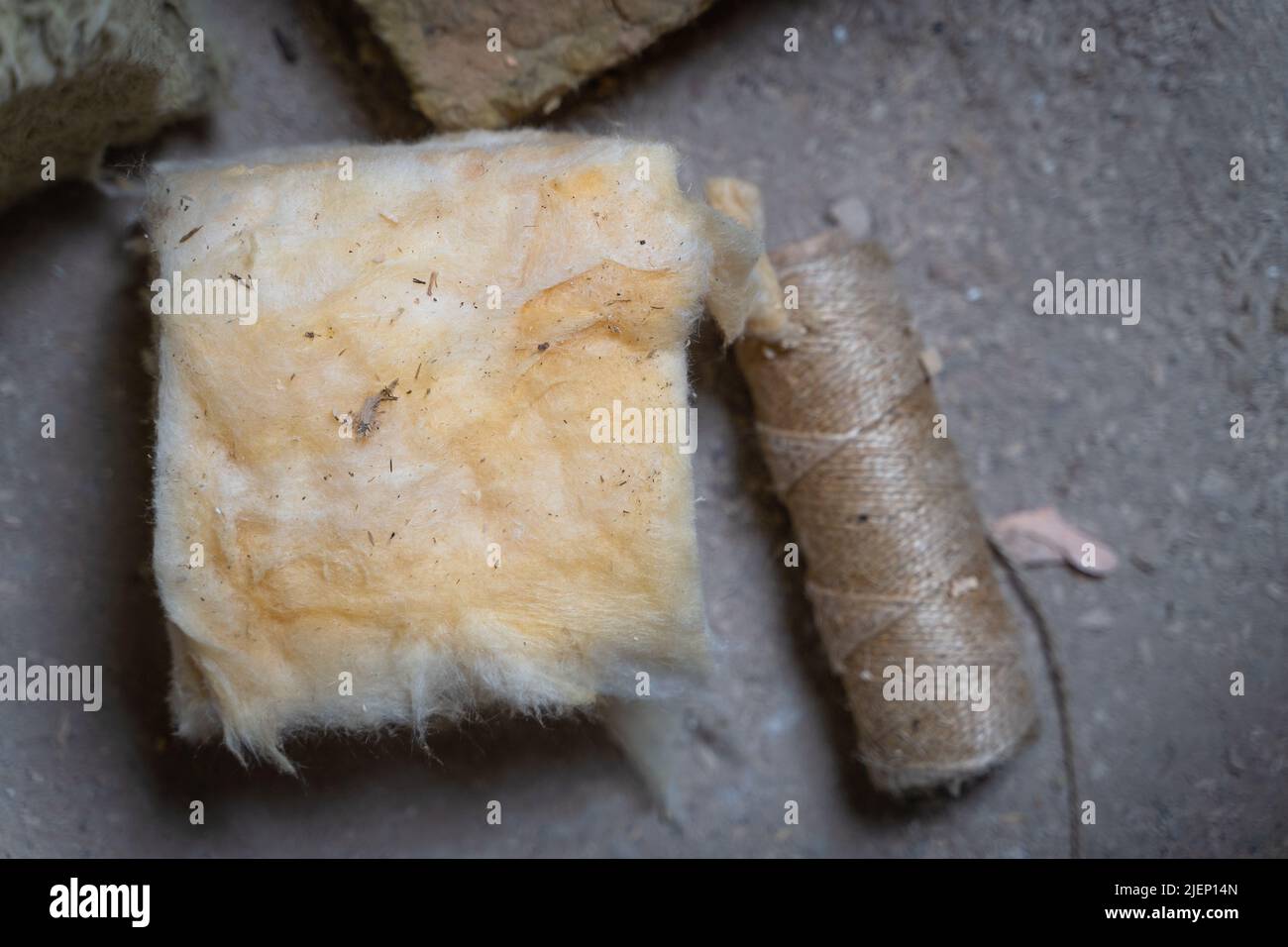 Primo piano di un taglio quadrato di lana di vetro gialla sullo sfondo di un filo di iuta, vista dall'alto Foto Stock