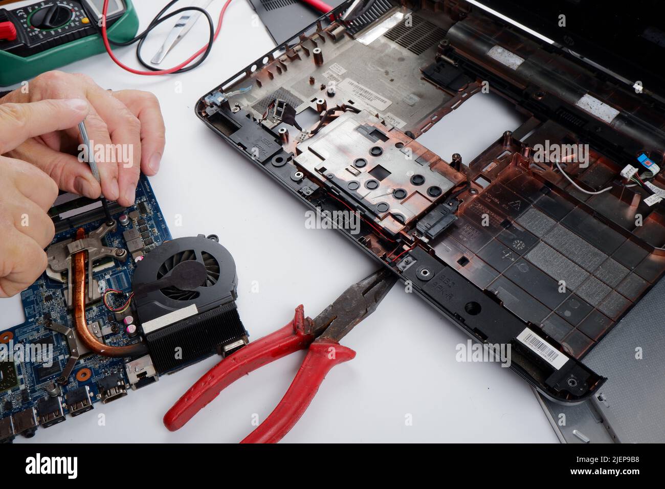 un tecnico addetto al ripristino del computer disassembla, ripara ed esegue la manutenzione preventiva per un computer portatile rotto. Foto Stock