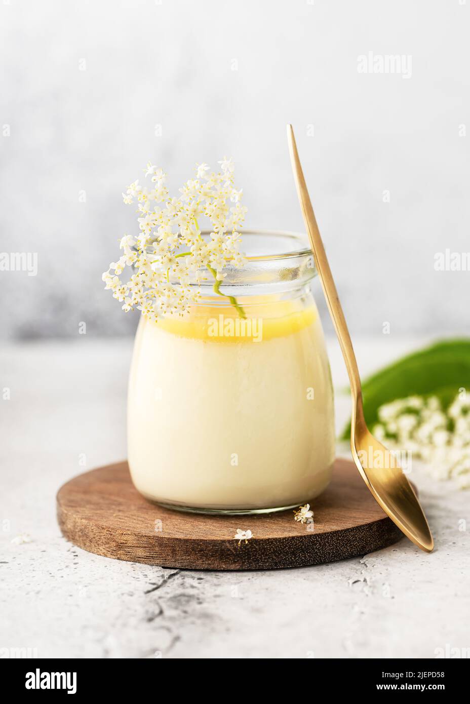 Dolce pane cotto fatto in casa, mousse o budino in una porzione di vaso di vetro con cagliata di limone e fiori freschi. Spazio di copia. Foto Stock
