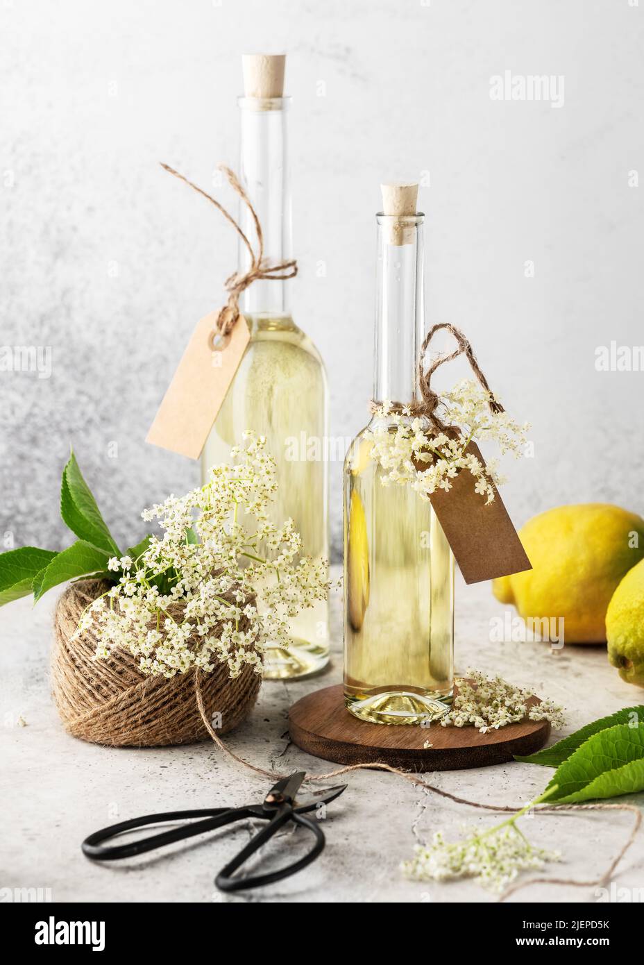 Sciroppo di sambuco fatto in casa in bottiglie di vetro per drink estivo con germogli di fiori di sambuco e limone. Concetto di bevande biologiche. Messa a fuoco selettiva. Foto Stock