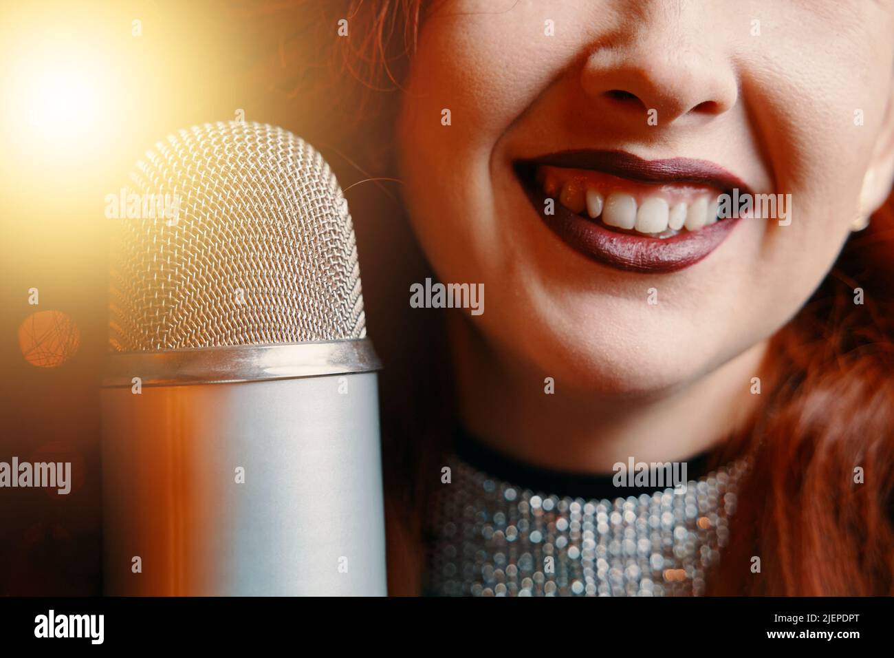 Sorridente cantante femminile e microfono retrò su sfondo bokeh sfocato. Foto Stock