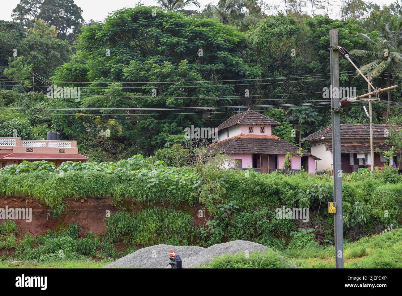 Una vecchia casa in un villaggio rurale quasi coperto da alberi vicino l'edificio. Vista dall'India. Foto Stock