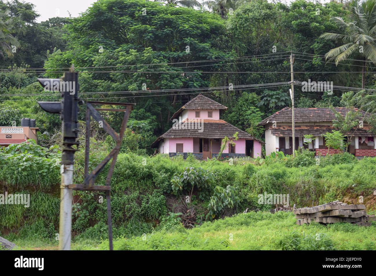 Una vecchia casa in un villaggio rurale quasi coperto da alberi vicino l'edificio. Vista dall'India. Foto Stock