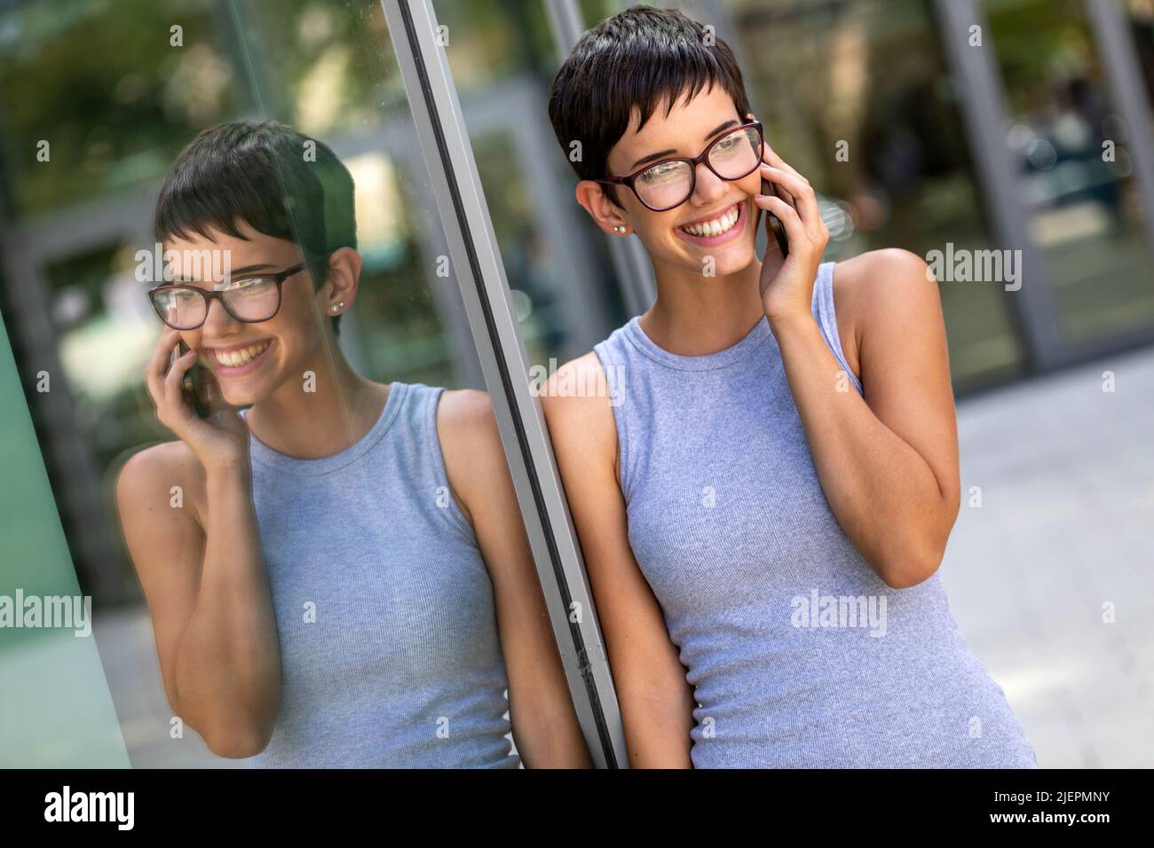 Bella donna d'affari di successo che usa lo smartphone davanti all'ufficio. Concetto di business tecnologico. Foto Stock