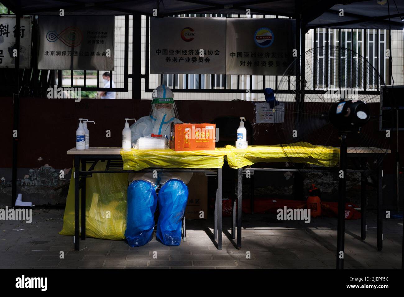 Un operatore medico in tuta protettiva si siede in una stazione di analisi degli acidi nucleici, a seguito dell'epidemia di coronavirus (COVID-19), a Pechino, Cina, 28 giugno 2022. REUTERS/Thomas Peter Foto Stock
