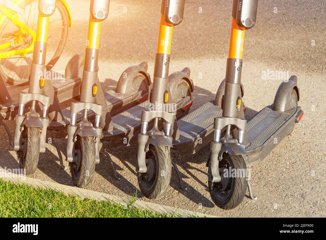 Scooter elettrici in fila sul parcheggio su asfalto. Sistema di noleggio biciclette in città, calci pubblici per la strada Foto Stock