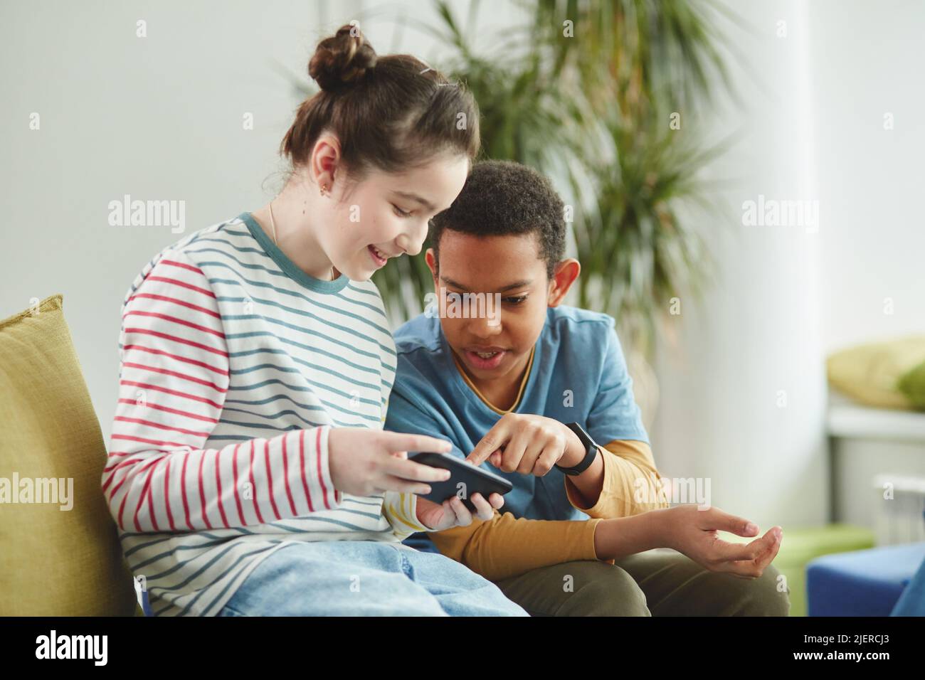 Ritratto di due bambini, ragazzo e ragazza con smartphone a scuola durante la pausa, entrambi vestiti con abiti colorati Foto Stock
