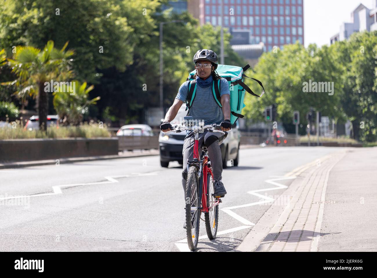 Corriere in bicicletta che consegna cibo Takeaway in traffico cittadino Foto Stock