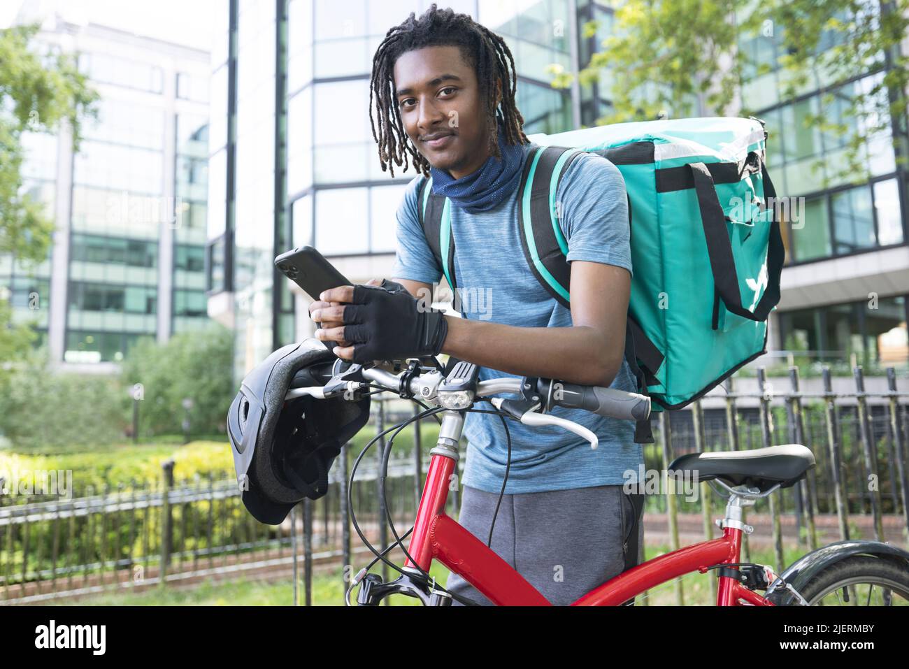 Ritratto di Corurier in bici consegna cibo da asporto con il cellulare Foto Stock