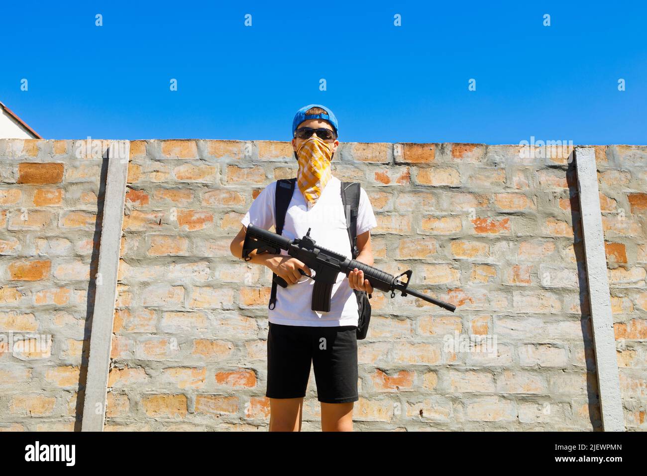 Ritratto di un giovane che tiene un fucile. Concetto di sparatutto per la scuola. Foto Stock