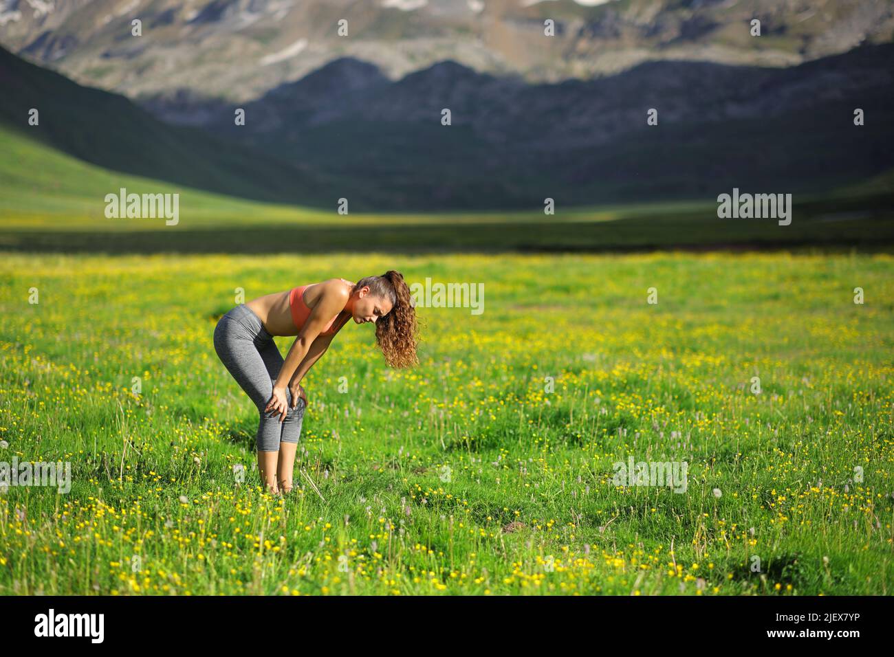 Ritratto laterale di un corridore esausto che riposa in un campo in alta montagna Foto Stock