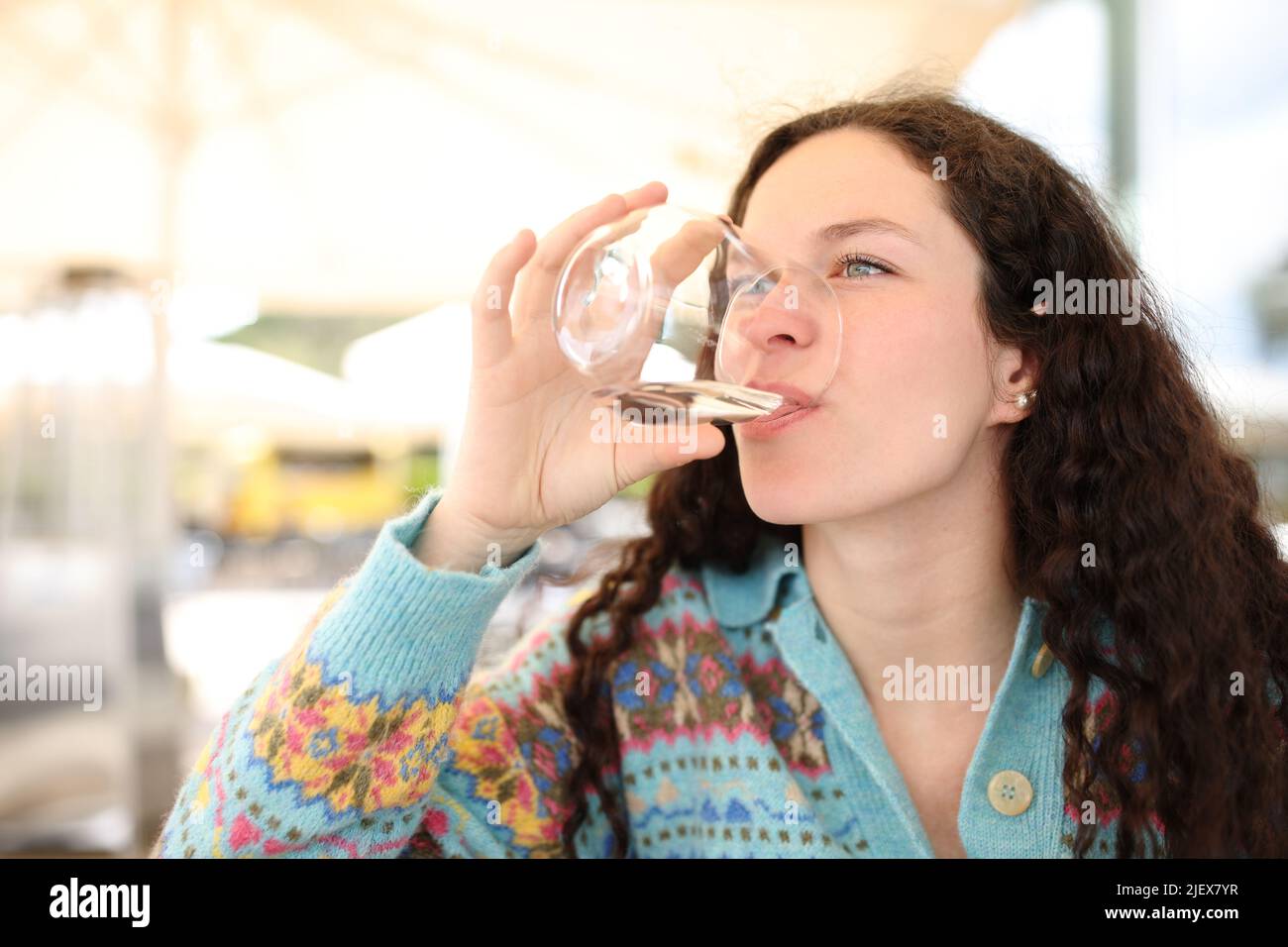 Donna che beve acqua dal vetro seduto in una caffetteria Foto Stock